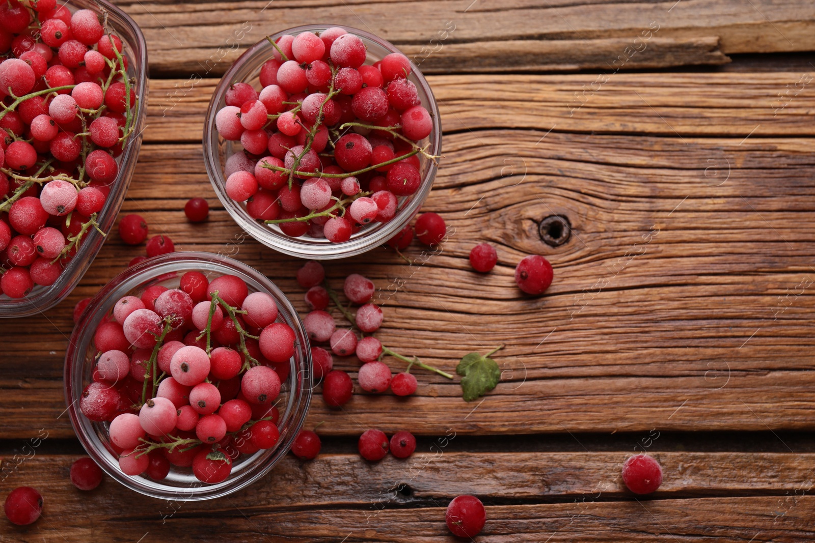 Photo of Ripe frozen red currants on wooden table, flat lay. Space for text