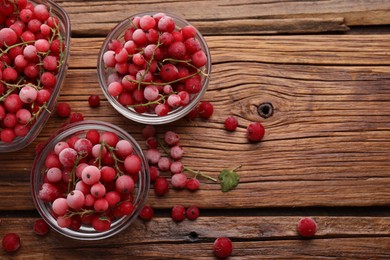 Photo of Ripe frozen red currants on wooden table, flat lay. Space for text