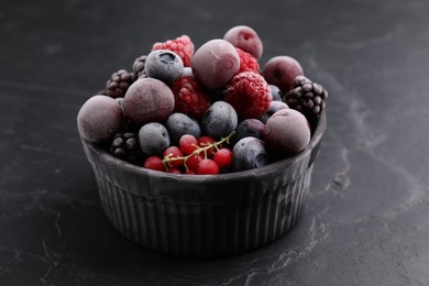 Photo of Mix of ripe frozen berries in bowl on dark textured table, closeup