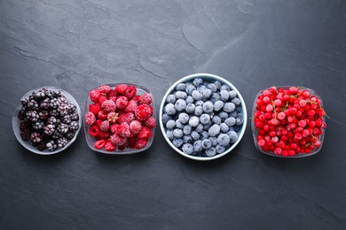 Photo of Different ripe frozen berries in bowls on dark textured table, flat lay