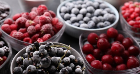 Photo of Different ripe frozen berries in bowls on table, closeup