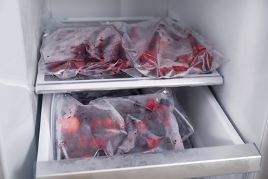 Photo of Different frozen berries in plastic bags in open fridge