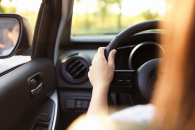 Photo of Woman behind steering wheel of modern car, closeup