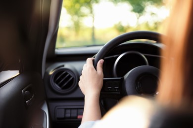 Photo of Woman behind steering wheel of modern car, closeup