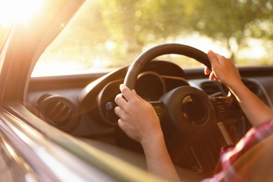 Photo of Woman behind steering wheel of modern car on sunny day, closeup
