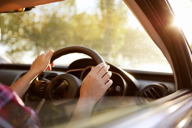 Photo of Woman behind steering wheel of modern car on sunny day, closeup