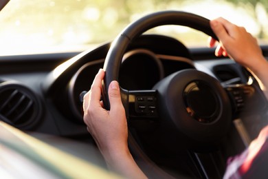 Photo of Woman behind steering wheel of modern car on sunny day, closeup