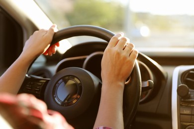 Photo of Woman behind steering wheel of modern car, closeup