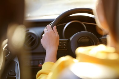 Photo of Woman behind steering wheel of modern car on sunny day, closeup
