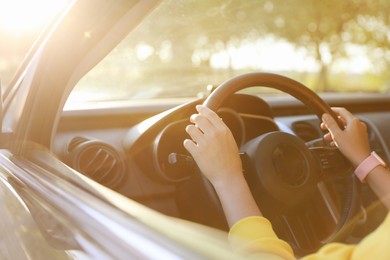 Photo of Woman behind steering wheel of modern car on sunny day, closeup
