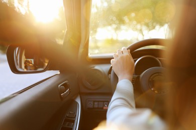 Photo of Woman behind steering wheel of modern car on sunny day, closeup