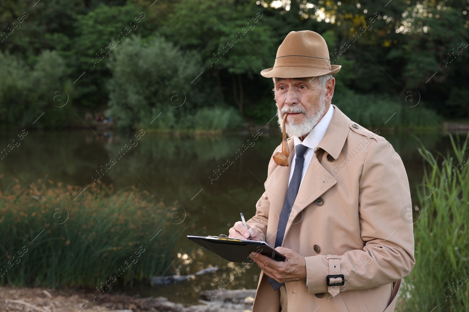 Photo of Forensic expertise. Detective with smoking pipe and clipboard working at crime scene near lake outdoors, space for text