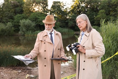 Photo of Forensic expertise. Detectives working at crime scene near lake outdoors
