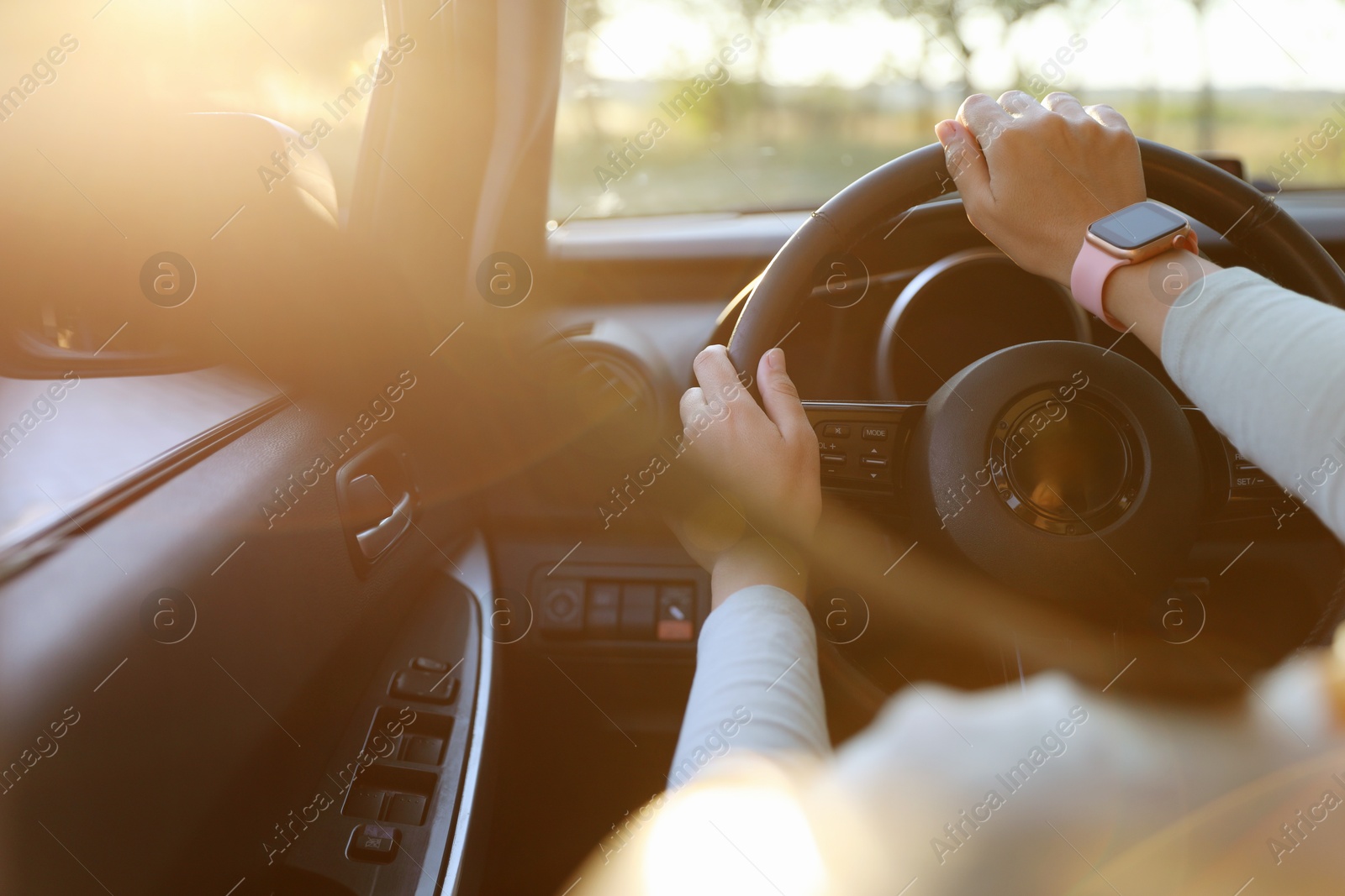 Woman behind steering wheel of modern car on sunny day, closeup Photo of Woman behind steering wheel of modern car on sunny day, closeup