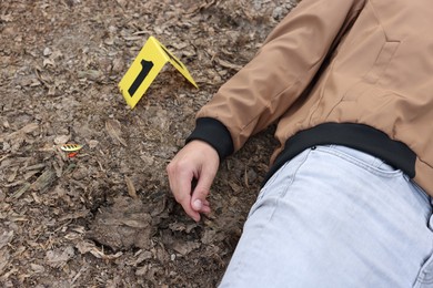 Photo of Forensic expertise. Crime scene with dead man's body and marker outdoors, above view