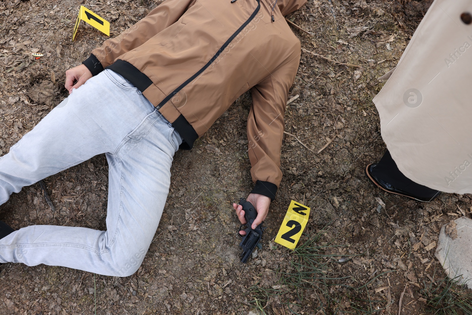 Photo of Forensic expertise. Detective near dead man's body at crime scene outdoors, top view