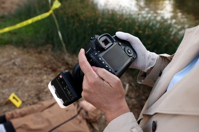 Photo of Forensic expertise. Detective with camera working at crime scene with dead man's body outdoors, closeup