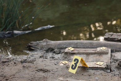Photo of Forensic expertise. Crime scene with evidence and marker near lake outdoors