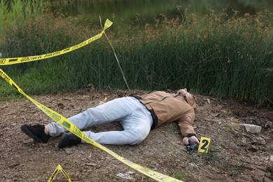 Photo of Forensic expertise. Crime scene with dead man's body and markers outdoors