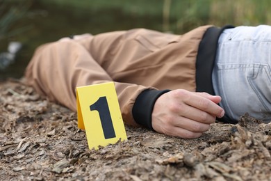 Photo of Forensic expertise. Crime scene with dead man's body and marker outdoors, closeup