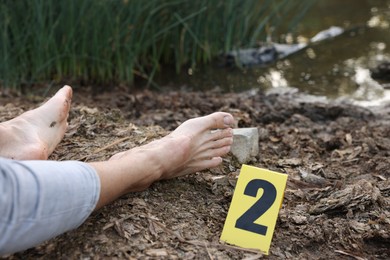 Photo of Forensic expertise. Crime scene with dead man's body and marker outdoors, closeup
