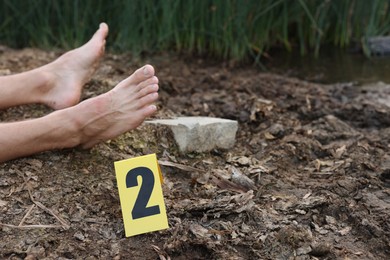 Photo of Forensic expertise. Crime scene with dead man's body and marker outdoors, closeup. Space for text