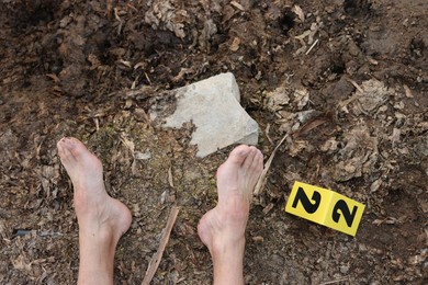 Photo of Forensic expertise. Crime scene with dead man's body and marker outdoors, top view