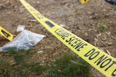 Photo of Forensic expertise. Crime scene with evidence, marker and police tape outdoors, closeup