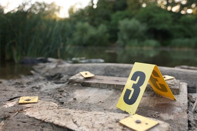 Photo of Forensic expertise. Crime scene with marker near lake outdoors, closeup. Space for text