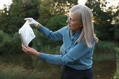 Photo of Forensic expertise. Detective with evidence working near lake outdoors