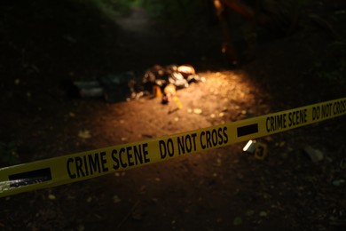 Photo of Forensic expertise. Crime scene with dead body and markers outdoors, focus on police tape