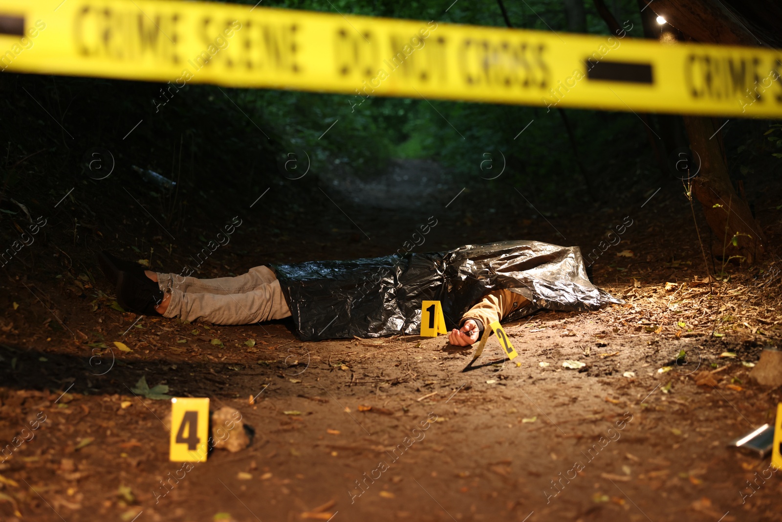 Photo of Forensic expertise. Crime scene with dead man's body and markers outdoors