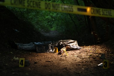 Photo of Forensic expertise. Crime scene with dead man's body and markers outdoors