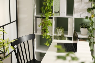 Photo of Biophilic interior design. Stylish workplace with laptop and houseplants in office