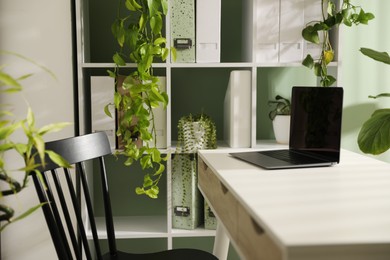 Photo of Biophilic interior design. Stylish workplace with laptop and houseplants in office