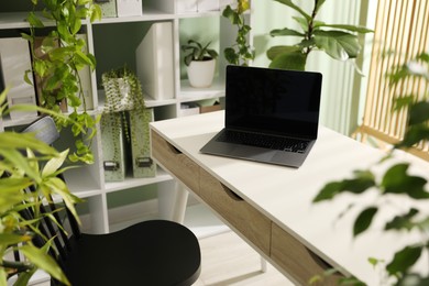 Photo of Biophilic interior design. Stylish workplace with laptop and houseplants in office