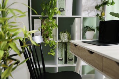 Photo of Biophilic interior design. Stylish workplace with laptop and houseplants in office