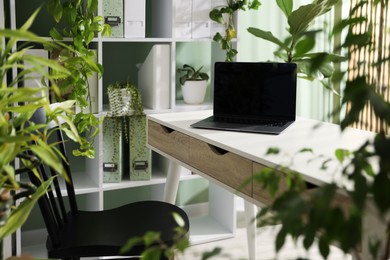 Photo of Biophilic interior design. Stylish workplace with laptop and houseplants in office