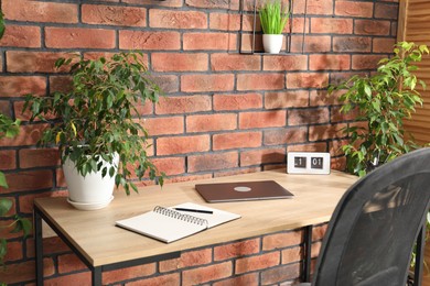 Photo of Stylish workplace with laptop, stationery and floral decor in office. Biophilic interior design