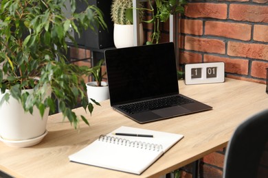 Photo of Stylish workplace with laptop, stationery and floral decor in office. Biophilic interior design