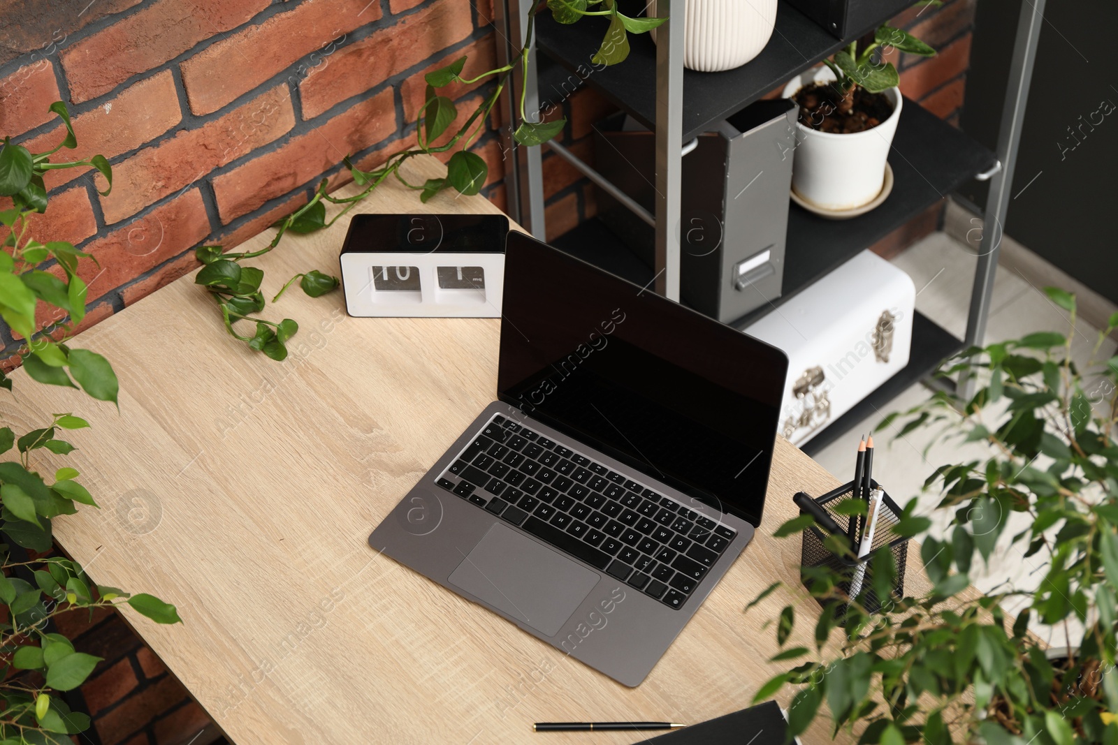 Stylish workplace with laptop, stationery and floral decor in office, above view. Biophilic interior design Photo of Stylish workplace with laptop, stationery and floral decor in office, above view. Biophilic interior design
