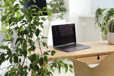 Photo of Stylish workplace with laptop and floral decor in office. Biophilic interior design
