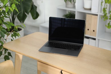 Photo of Stylish workplace with laptop and floral decor in office. Biophilic interior design