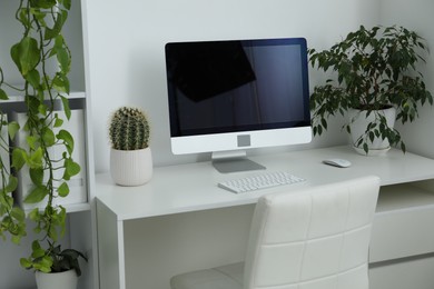 Photo of Stylish workplace with modern computer and floral decor in office. Biophilic interior design