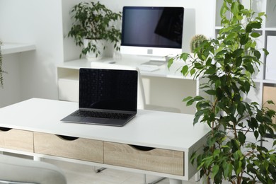 Photo of Stylish workplace with laptop, modern computer and floral decor in office. Biophilic interior design