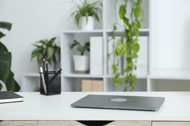 Photo of Stylish workplace with laptop, stationery and floral decor in office. Biophilic interior design