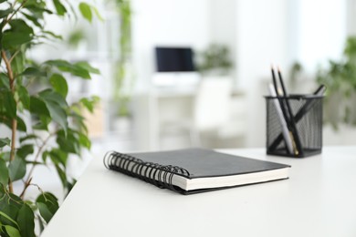 Photo of Stylish workplace with stationery and floral decor in office, closeup. Biophilic interior design