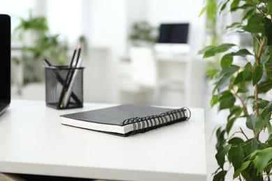 Photo of Stylish workplace with stationery and floral decor in office, closeup. Biophilic interior design