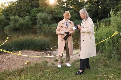 Photo of Forensic expertise. Detectives working at crime scene near lake outdoors, space for text