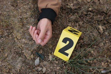 Photo of Forensic expertise. Crime scene with dead man's body and marker outdoors, top view